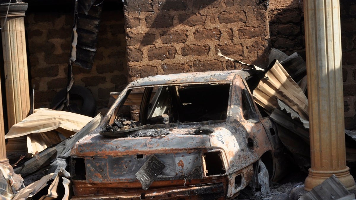 A burnt vehicle at a burnt out Nigerian home