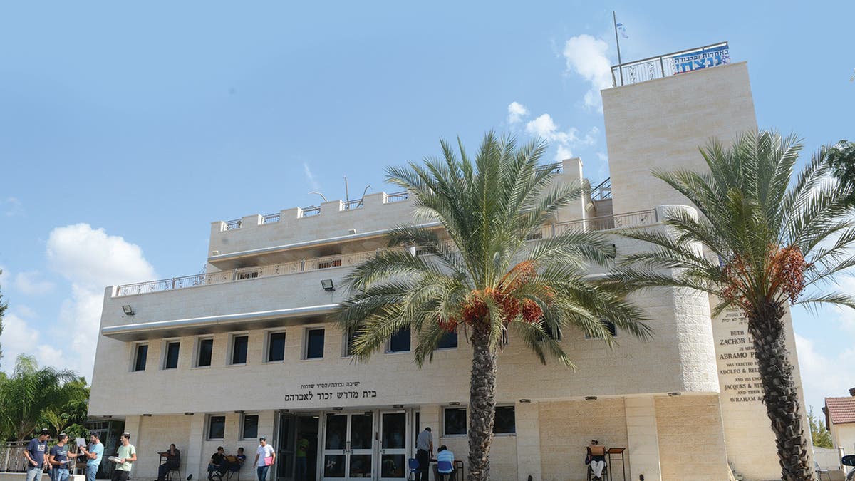 People and palm trees outside of Max and Ruth Schwartz Hesder Yeshiva 
