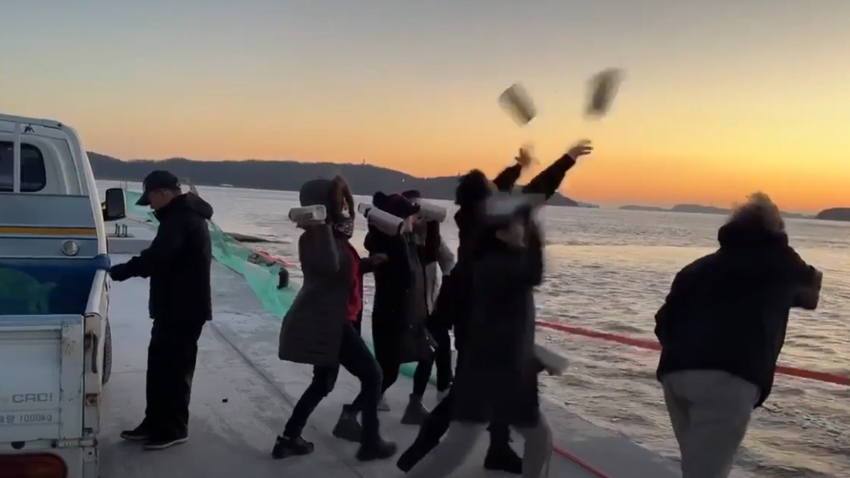 People throwing bottles with rice, American one dollar bill, and a Bible on a flash drive off a boat into the Yellow Sea 