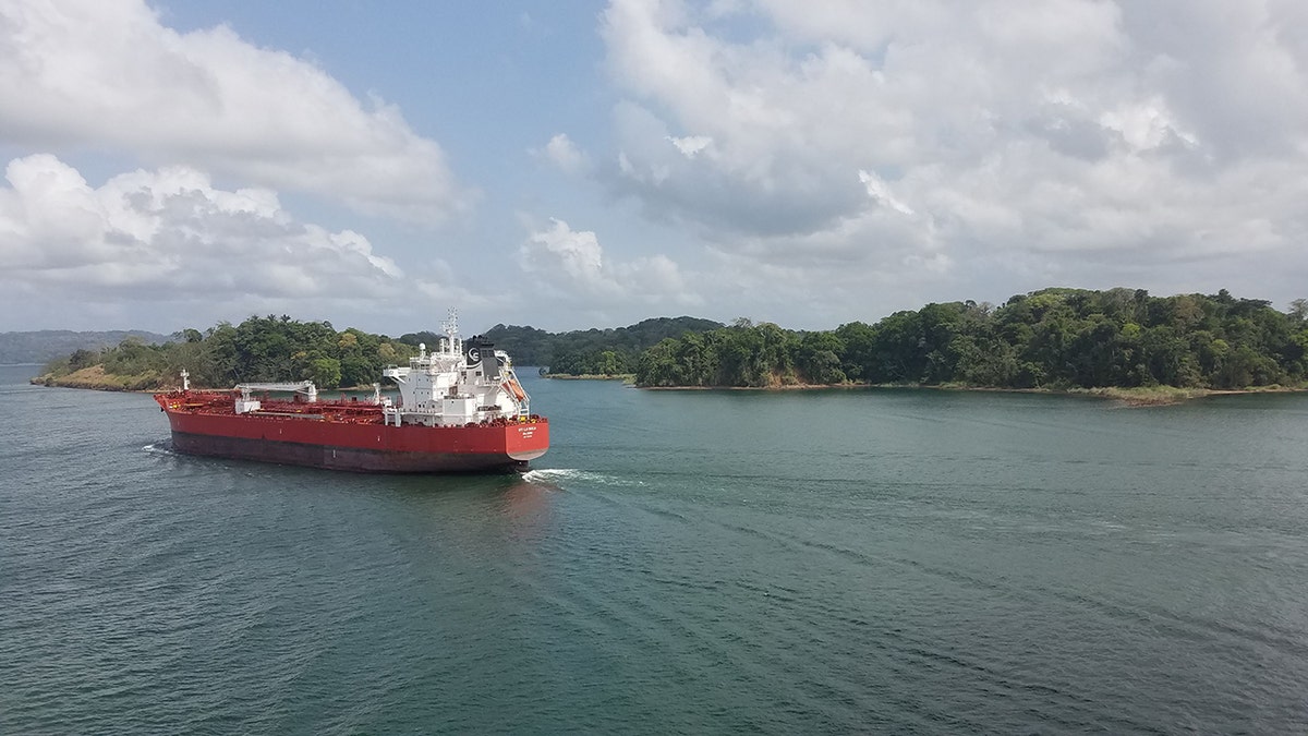 Red and white vessel traveling across Gatun Lake