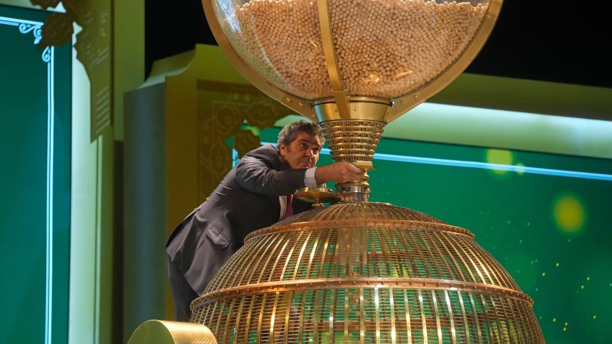 A worker supervises the moment when lottery balls are filled into a drum before a draw