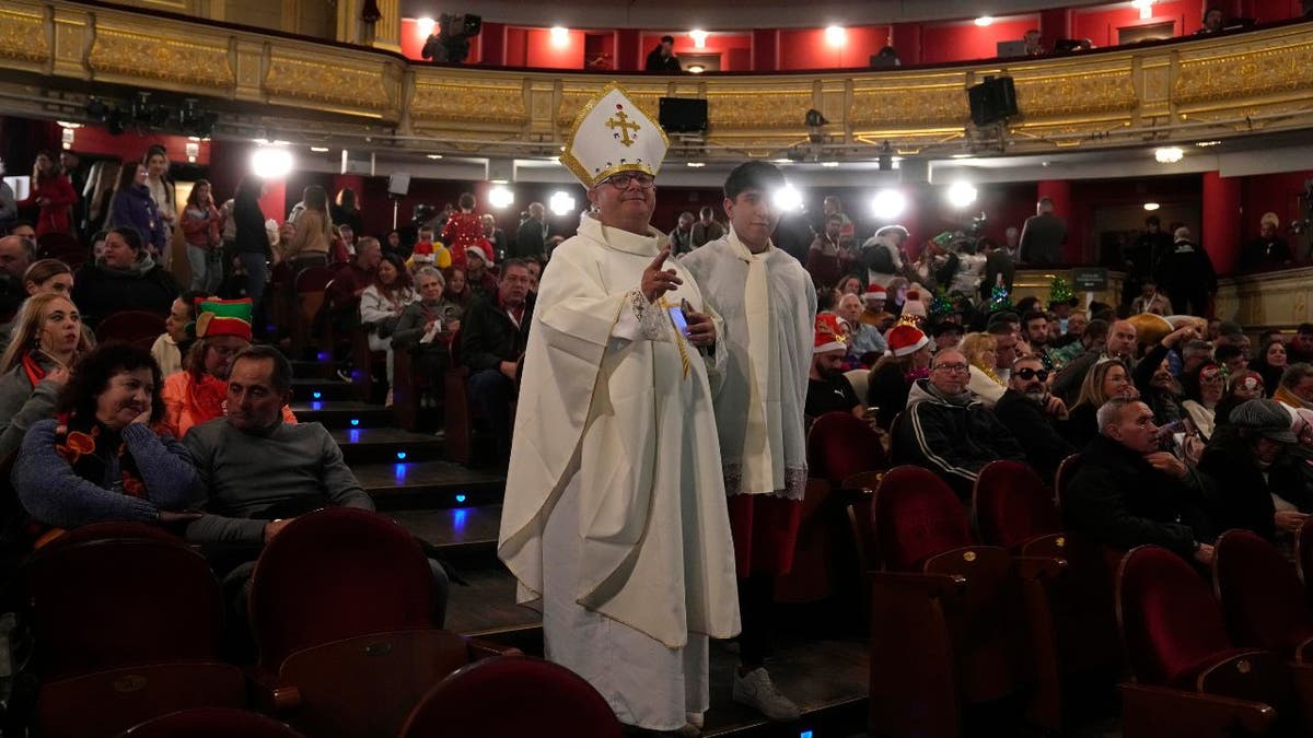 People in costumes wait for the start of Spain's Christmas draw in a theater.