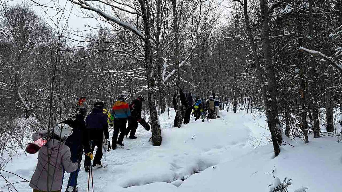 skiers and snowboarders hiking through snow