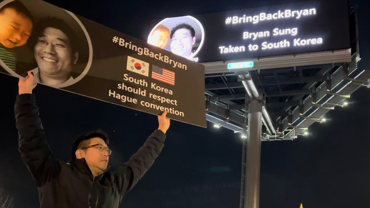 Jay Sung holds a poster demanding South Korean officials return his son Bryan
