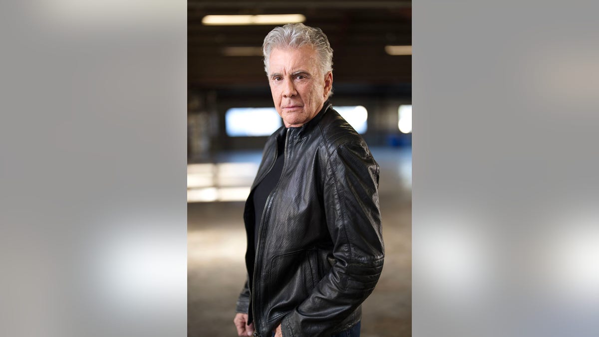 John Walsh looking to the side in a black leather jacket