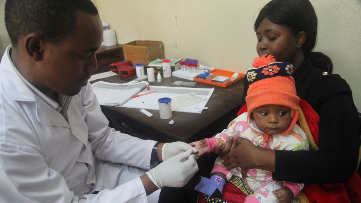 A doctor tests a child for malaria