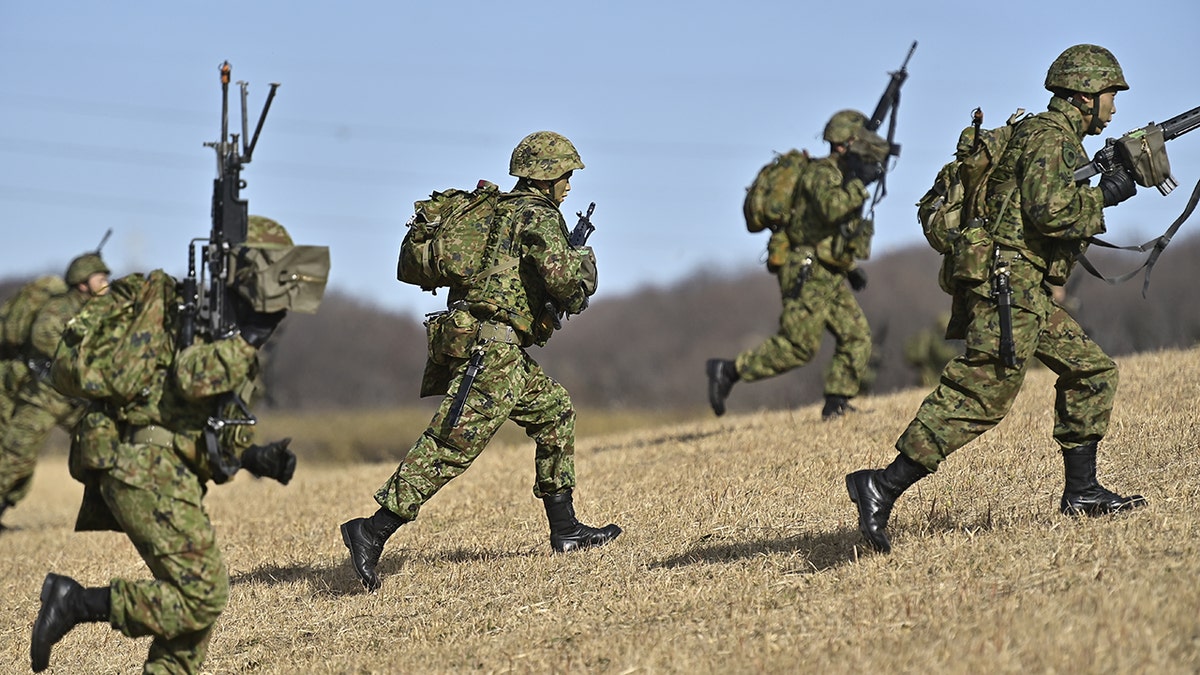 Japanese soldiers in uniform running with rifles