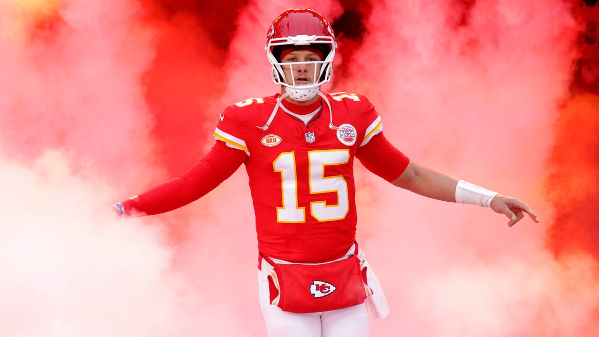 Patrick Mahomes of the Kansas City Chiefs running onto the field, surrounded by plumes of red and white smoke.