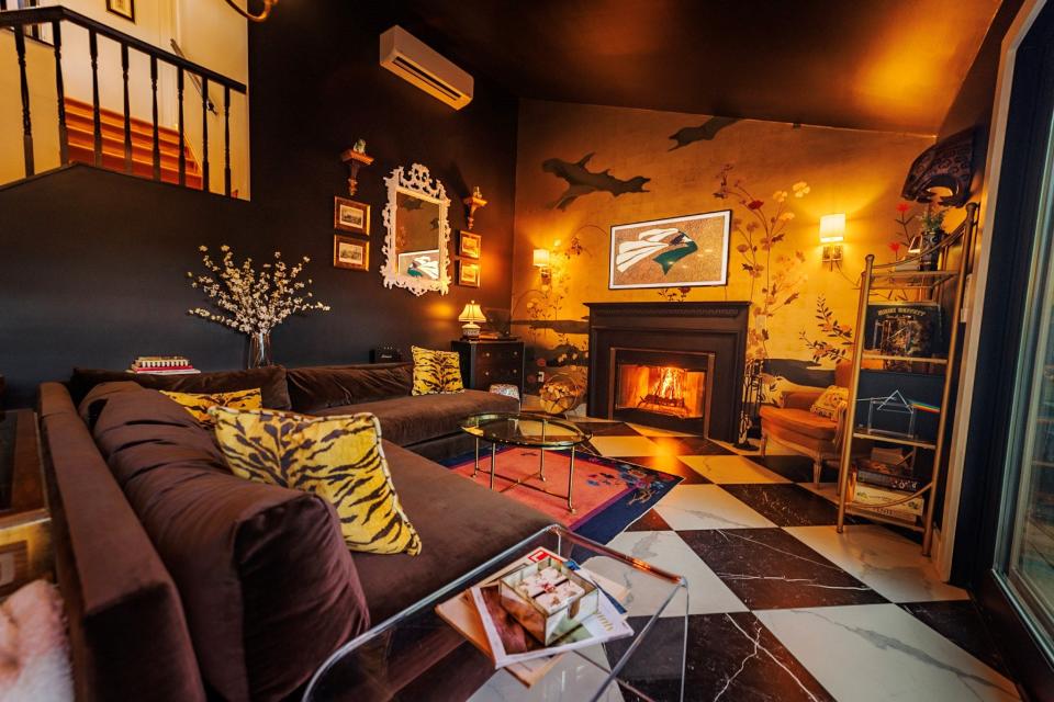 The living room at Killercat Mountain House in Hunter, NY features everything you can think of for a weekend getaway including a wood-burning fire, a record player, lots of games and a "killer" mountain view.
