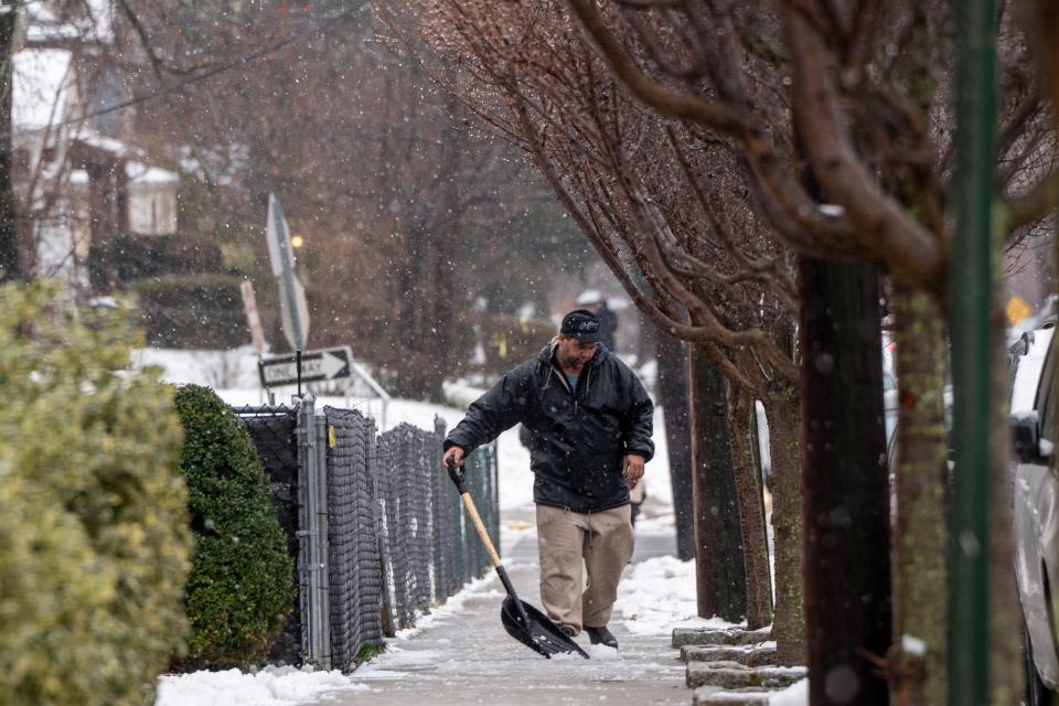 Jan 7, 2024; Passaic, NJ, USA; A man shovels slush from the sidewalk along High Street as a mix of rain and snow falls.