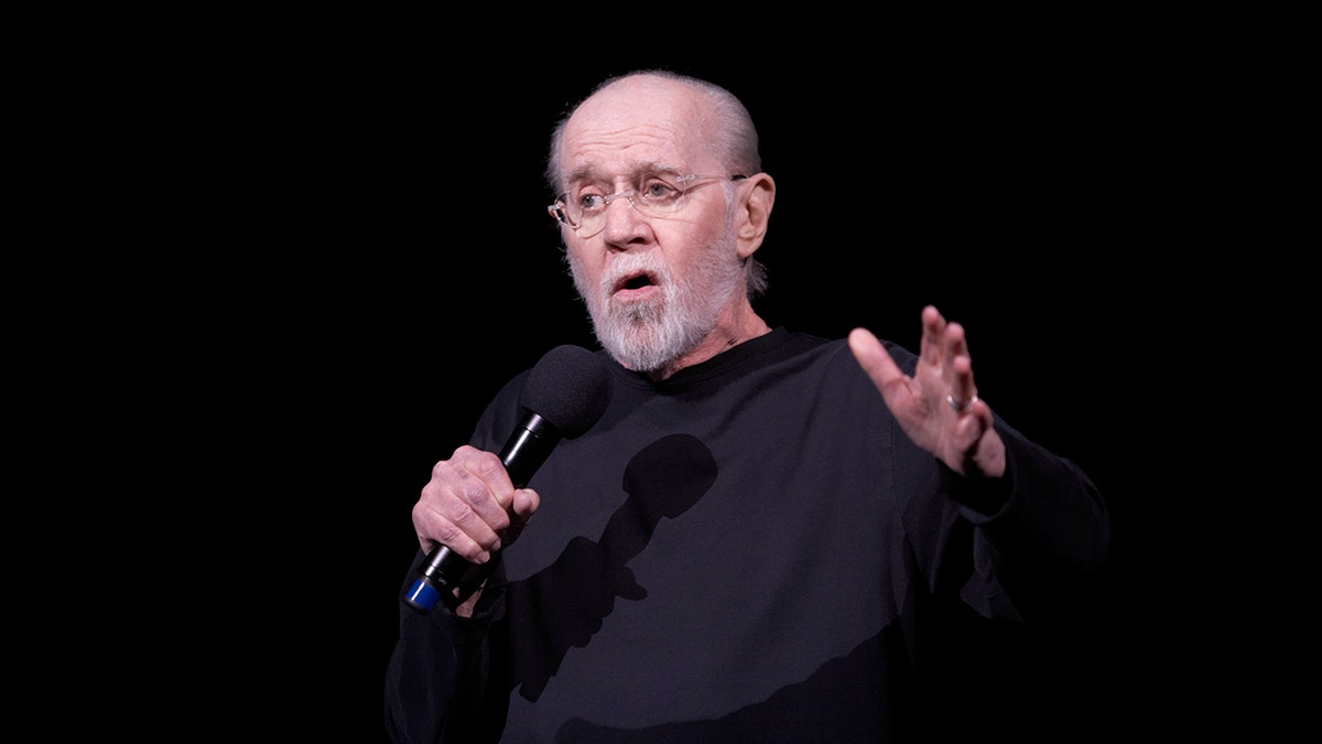 George Carlin on stage with a microphone