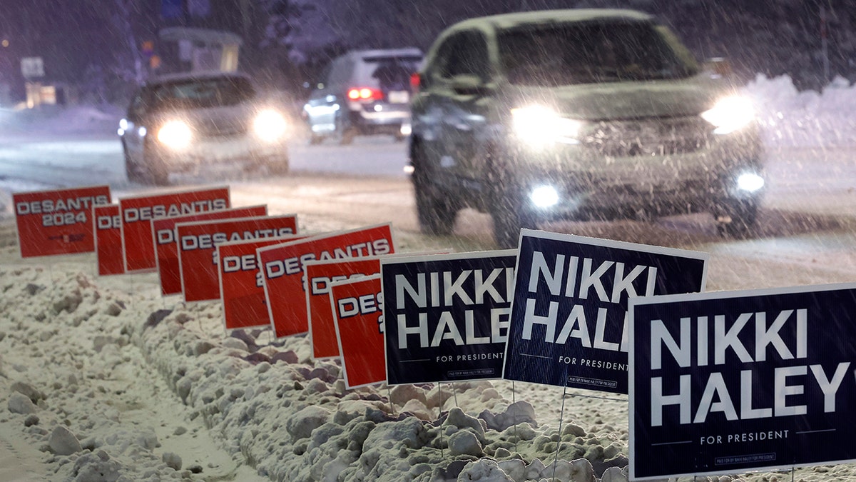 DeSantis and Haley for president signs in the snow in Iowa, cars driving by on street with headlights
