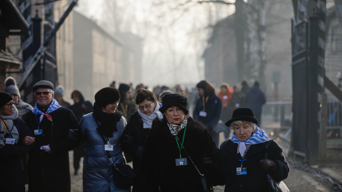 Survivors of the Auschwitz concentration camp walk by the main gate