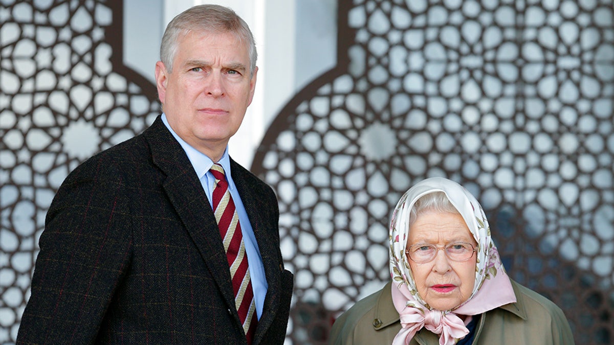 Prince Andrew standing next to queen Elizabeth who is wearing a scarf wrapped around her head