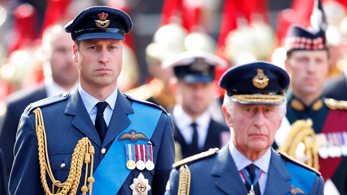 Prince William standing next to his father King Charles as they both wear military uniforms