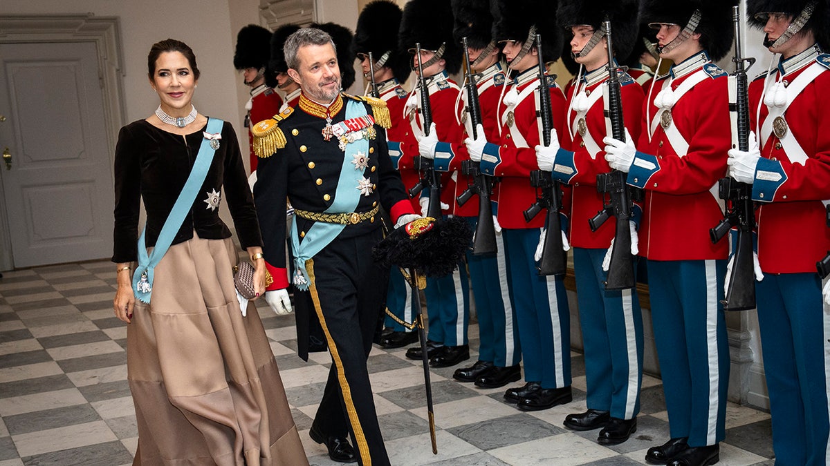 Crown Prince Frederik and Crown Princess Mary walking near a line of military guards