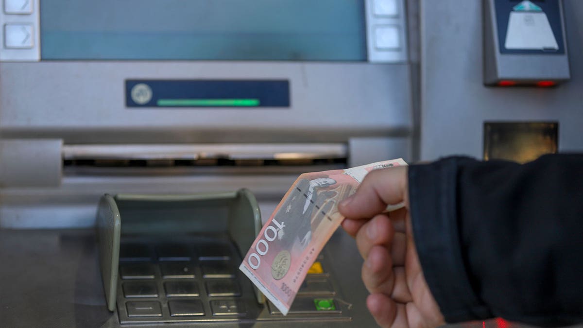 A man withdraws Serbian dinars from a bank machine