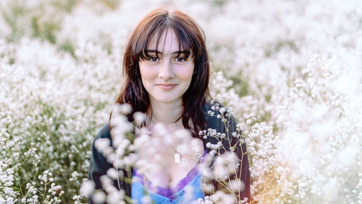 Ella Jones sits in a field of flowers