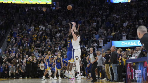 Denver Nuggets center Nikola Jokic (15) hits a 3-pointer over Golden State Warriors forward Kevon Looney (5) to give the Nuggets the win in an NBA basketball game Thursday, Jan. 4, 2024, in San Francisco. (AP Photo/Loren Elliott)