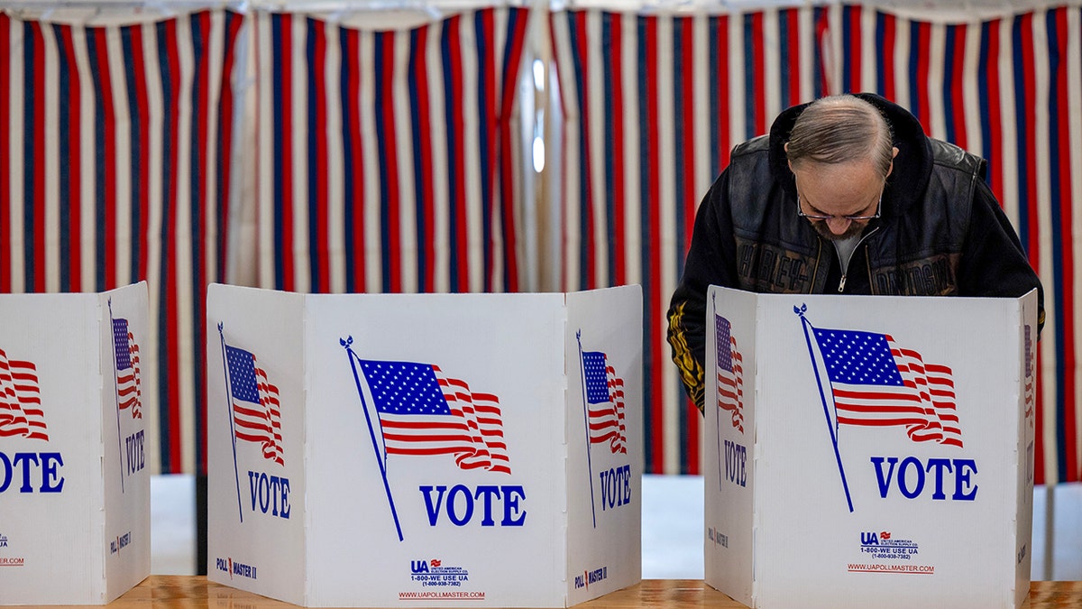 Voting booths, man with glasses, mustache, in jacket voting