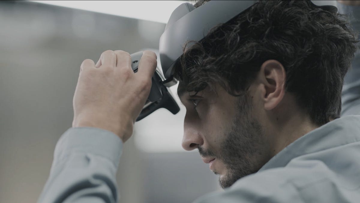 A man flipping up a mixed reality headset visor on his head