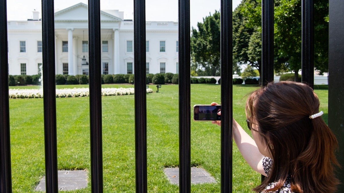 Tourists visit the fence line on the north side of the White House