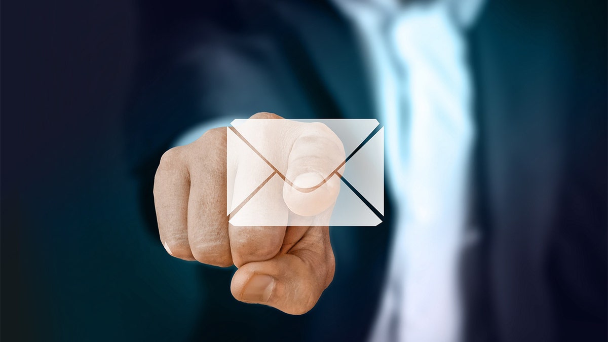 A man wearing a suit pointing his finger at a semi-clear email envelope on the screen