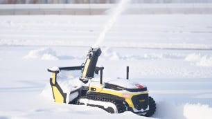 Snow plow robot blowing snow in a yard.