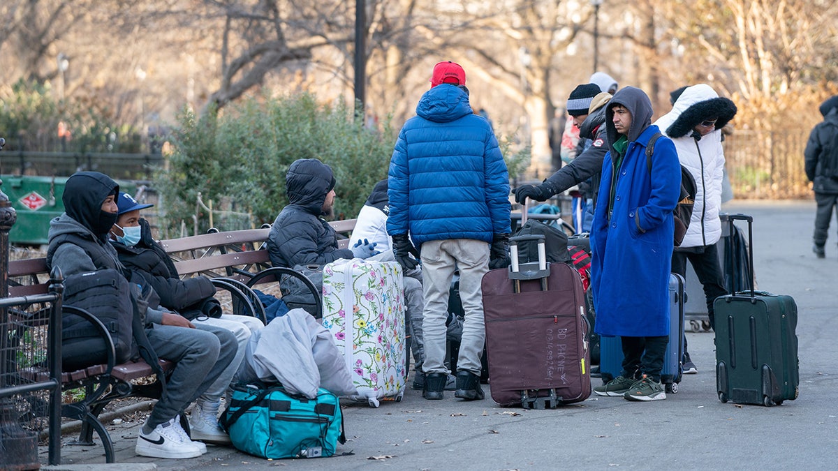 Migrants wait with luggage in NYC