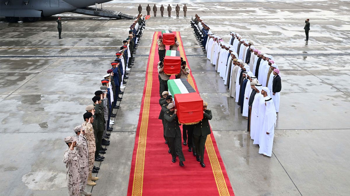 three flag-draped caskets carry by Emirati armed forces after coming off of an aircraft