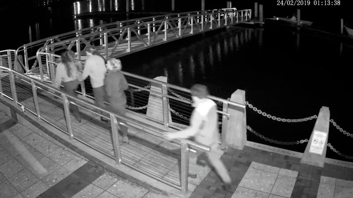 Black and white surveillance video showing young people on a dock at night