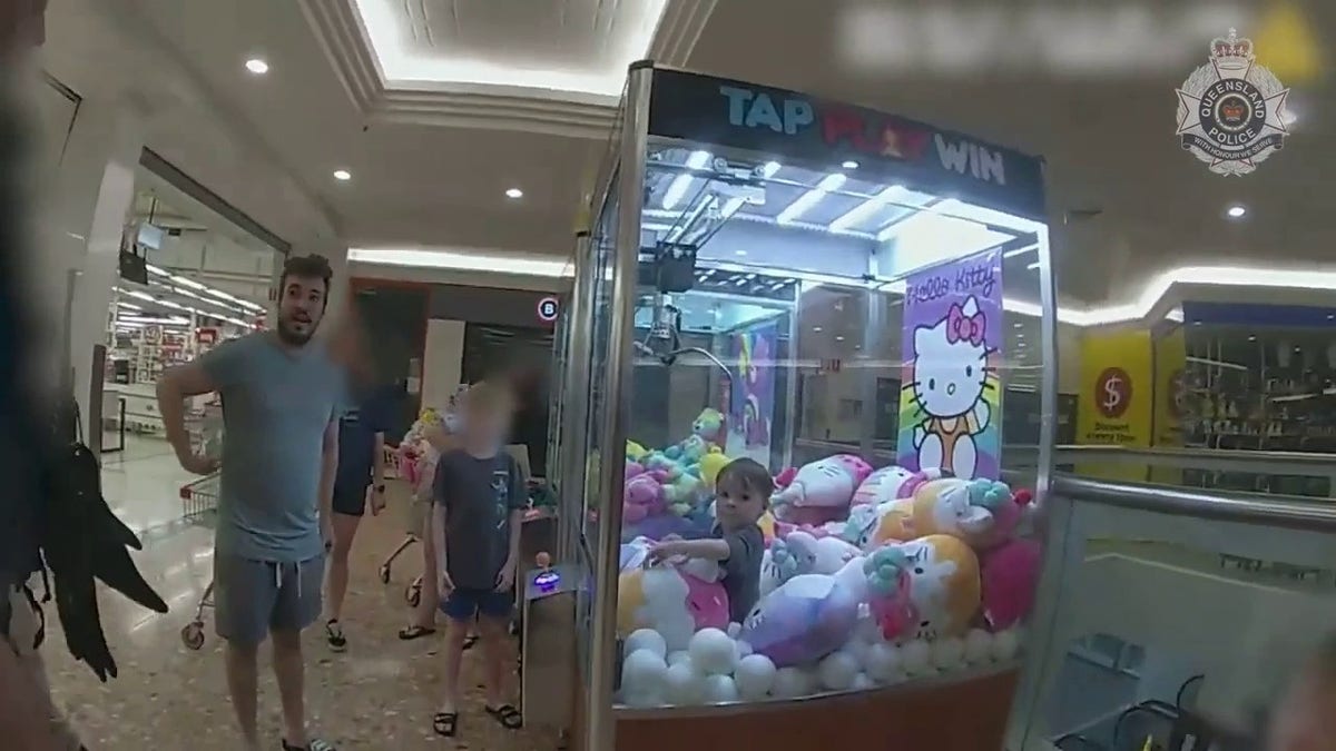 father watches toddler inside claw machine