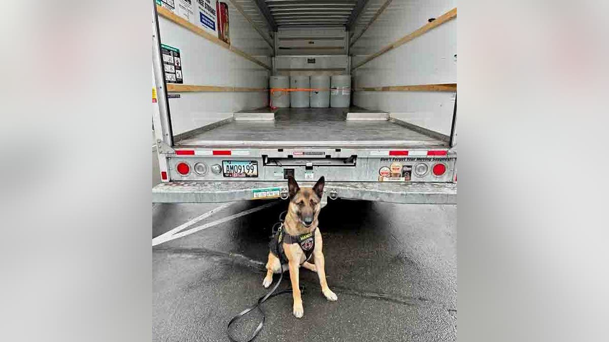 K-9 in front of truck with barrels of liquid heroin
