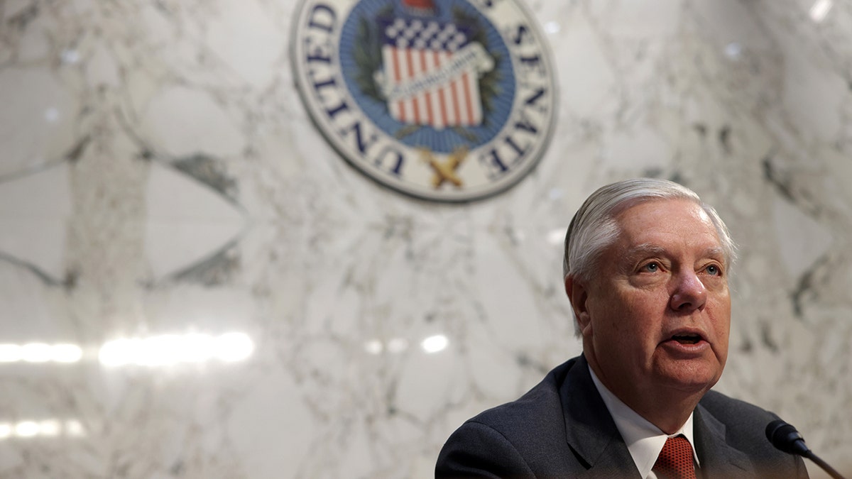 Sen. Lindsey Graham speaking (right corner of the photo) chest up, in front of marble wall, United States Senate sign behind him