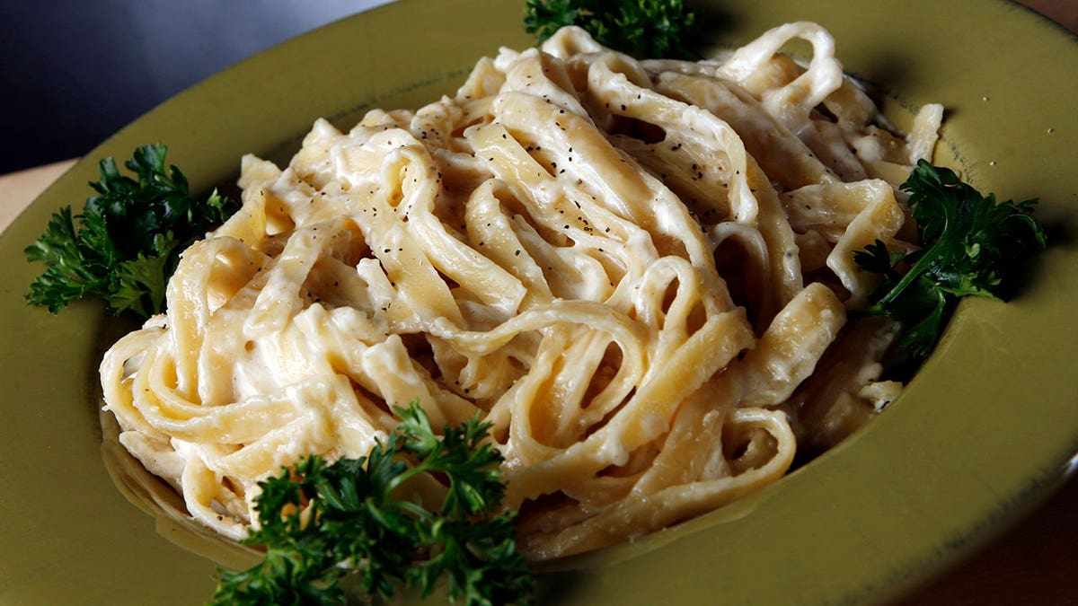 Fetucine alfredo pasta on a green dish with garnish