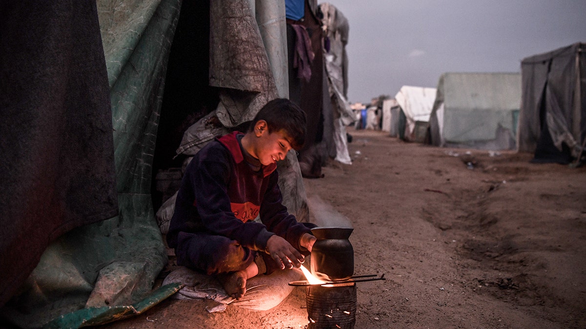 A Palestinian boy sitting by a tent