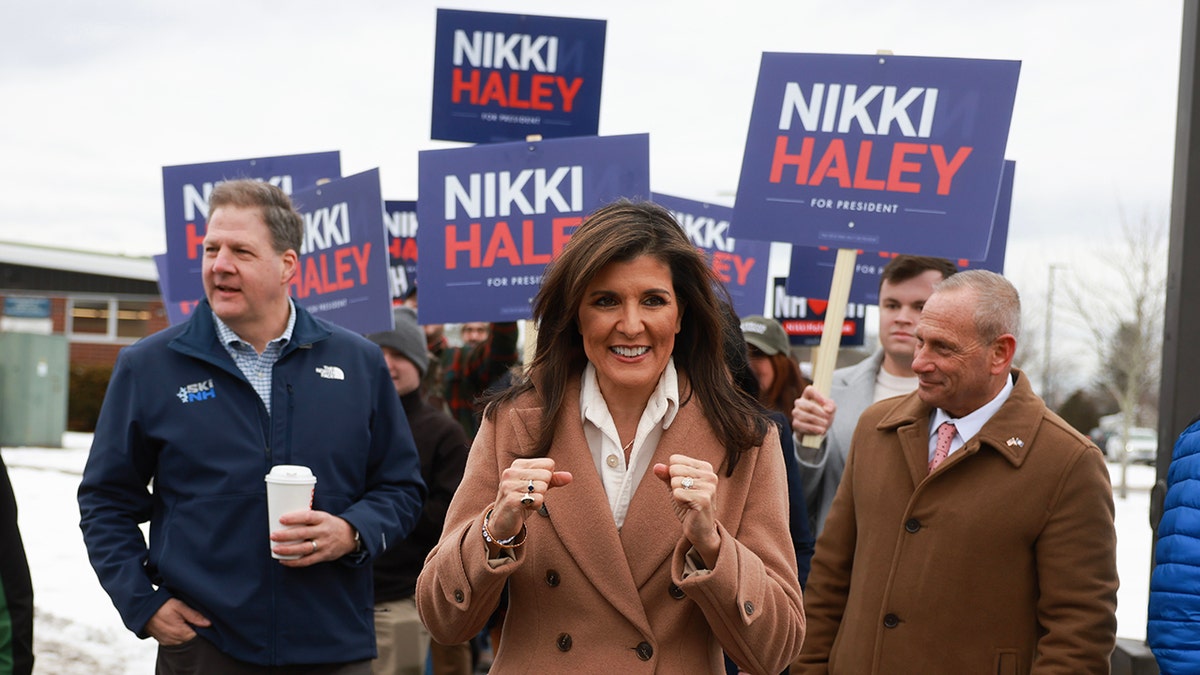New Hampshire Gov. Chris Sununu walking with Nikki Haley who is smiling with fists in mid air
