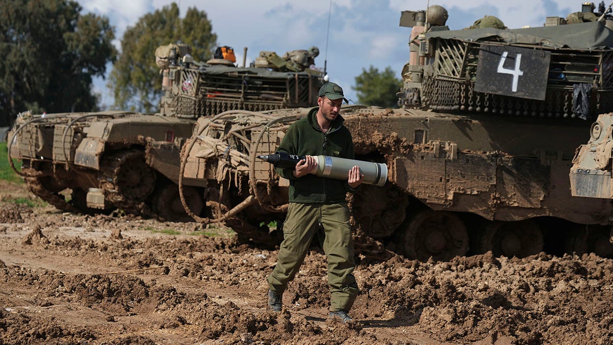 Israeli soldier carries tank shell