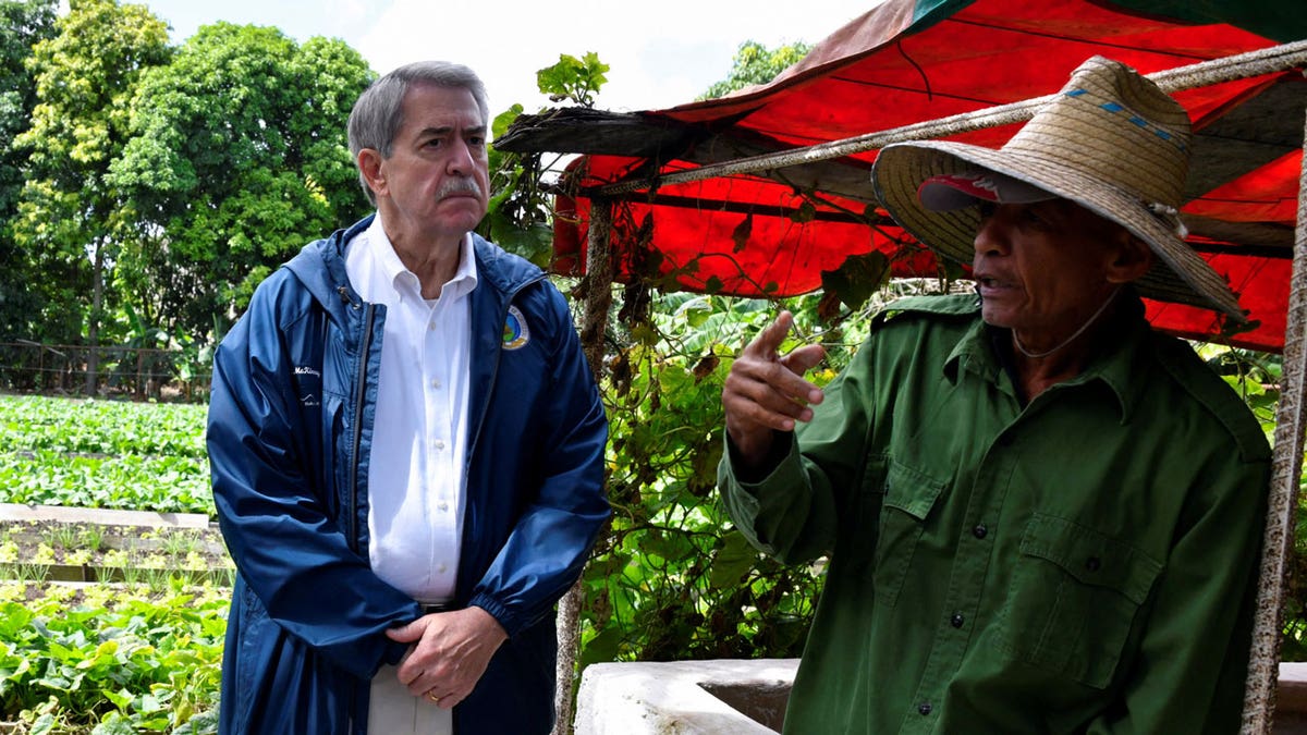 Ted McKinney, CEO of the National Association of State Departments of Agriculture, listens to a Cuban farmer 