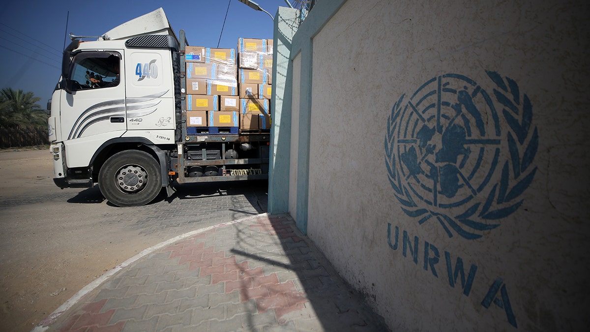 The United Nations Relief and Works Agency for Palestine Refugees logo on a wall adjacent to an aid truck delivering supplies