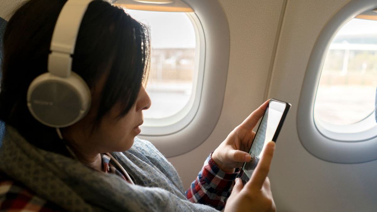 A woman talks on a phone aboard a plane.