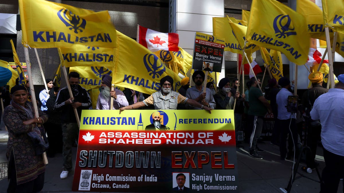 A group of protesters hold yellow flags with the word Khalistan, as well as a banner with the picture of Sikh separatist leader Hardeep Singh