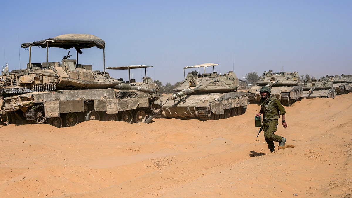 Israeli soldier walking past tank