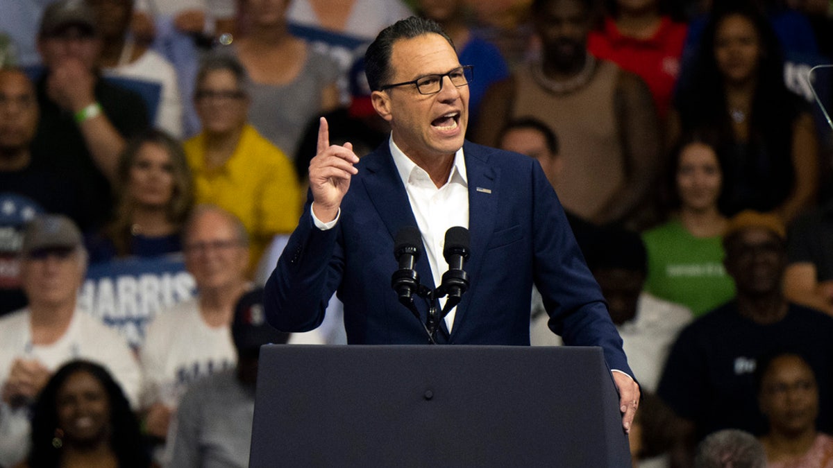 Josh Shapiro wearing a blue suit while speaking at a rally