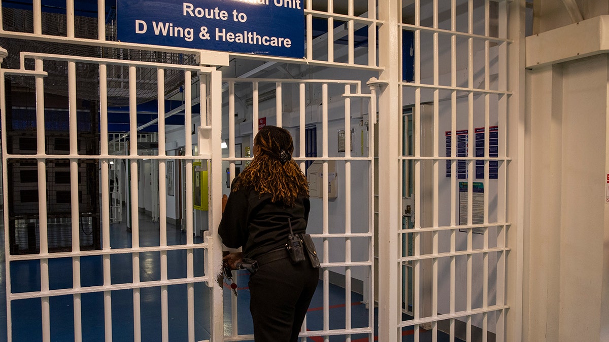 A female Prison Officer locks the metal gate entrance to D Wing and Healthcare Wing of His Majesty's Prison, Pentonville, London, United Kingdom.