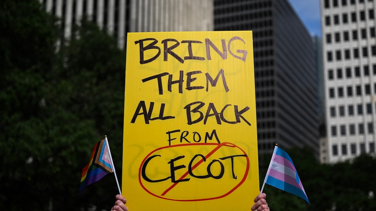 A person holds up a sign referencing the CECOT prison in El Salvador during a demonstration against President Donald Trump and his immigration policies in Houston on May 1, 2025.