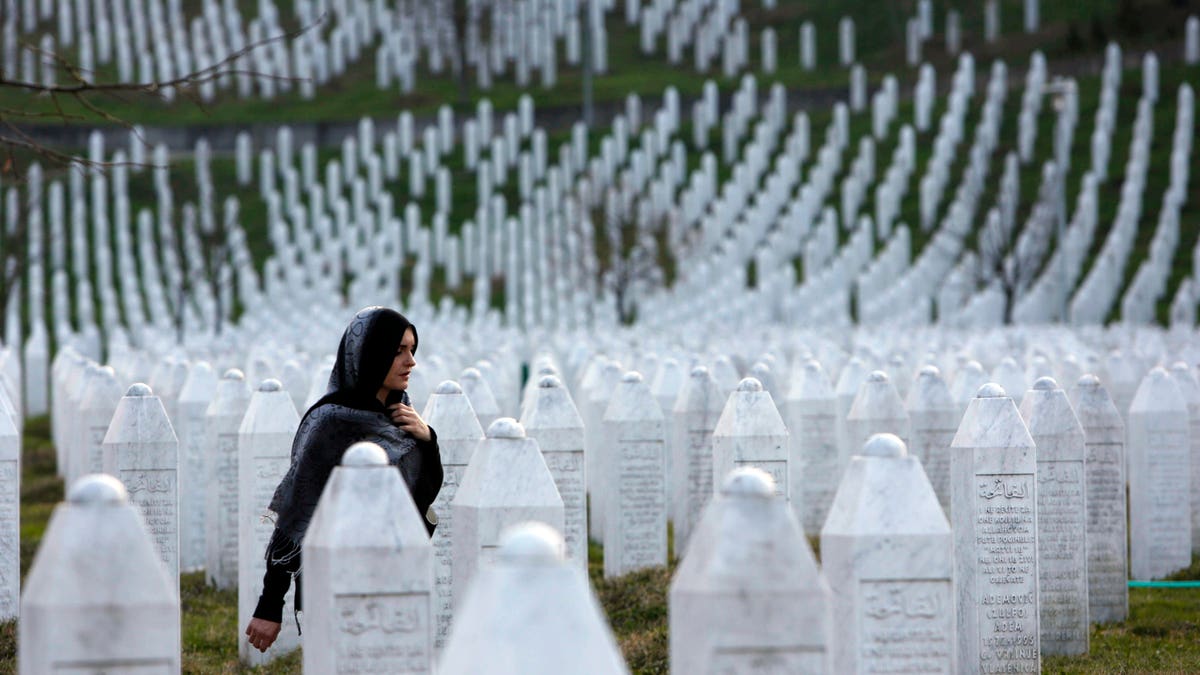 In this photo taken on Sunday, March 20, 2016, a Bosnian woman walks among gravestones at Memorial Centre Potocari near Srebrenica, Bosnia and Herzegovina. Former Bosnian Serb leader Radovan Karadzic will hear his verdict on Thursday, March 24, 2016 and prosecutors of the U.N. war crimes tribunal have called for life in prison for 11 counts of war crimes, including genocide he is accused of having masterminded during Bosnia's 1992-95 war. (AP Photo/Amel Emric)
