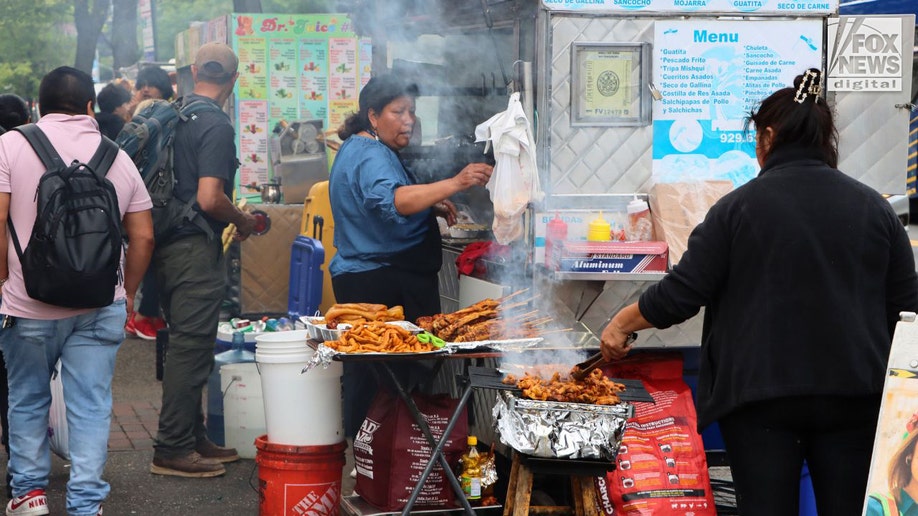 Female vendors cooking meet on a sidewalk.