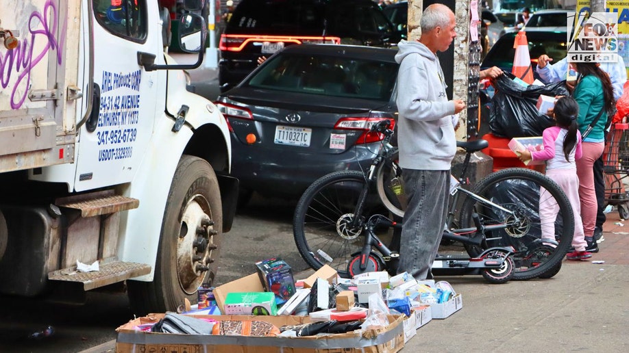 A man selling various items in Roosevelt Avenue in Queens, New York City.