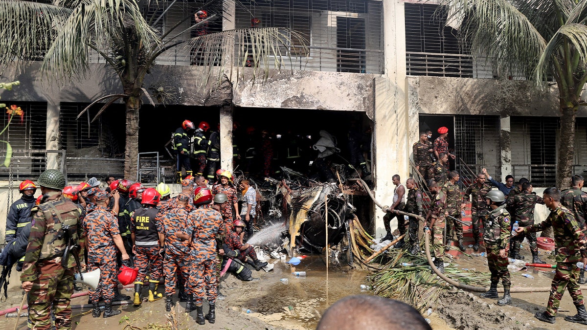 officials next to the wreckage of a jet that crashed into a building